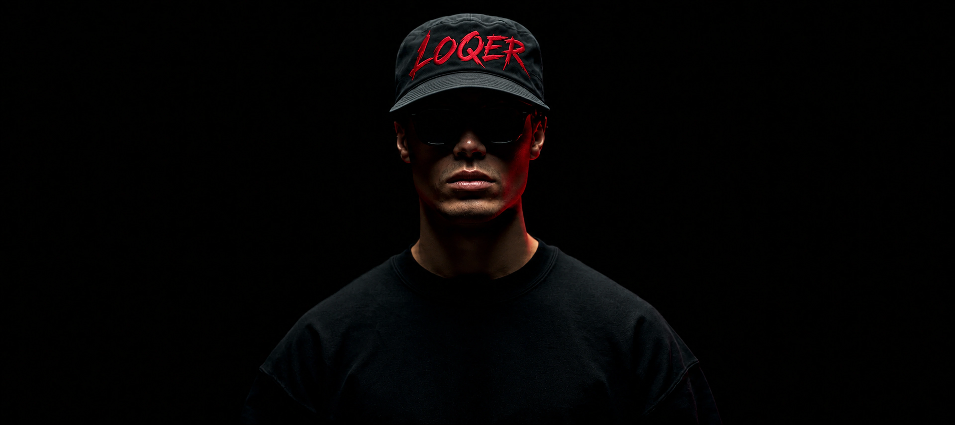 Человек в фирменной кепке LOQER на тёмном фоне